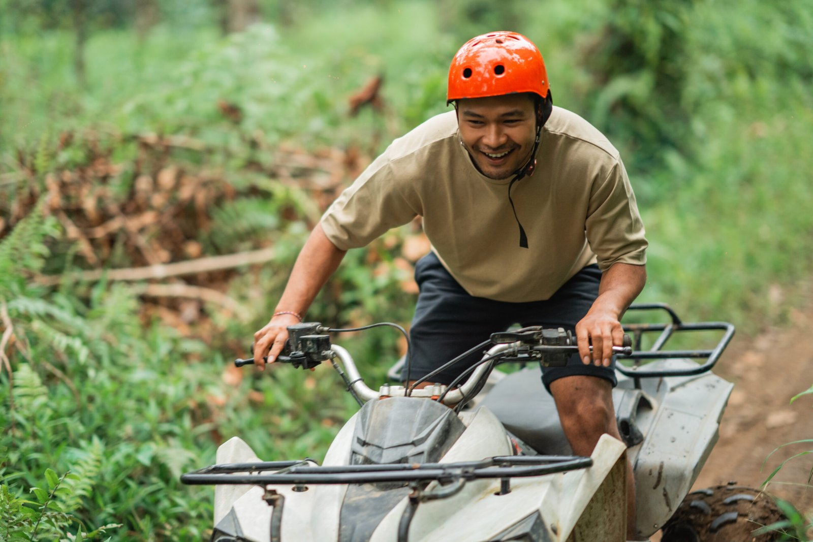 asian man smiling feeling the excitement while go through the difficult terrain at atv track inside the amusement park