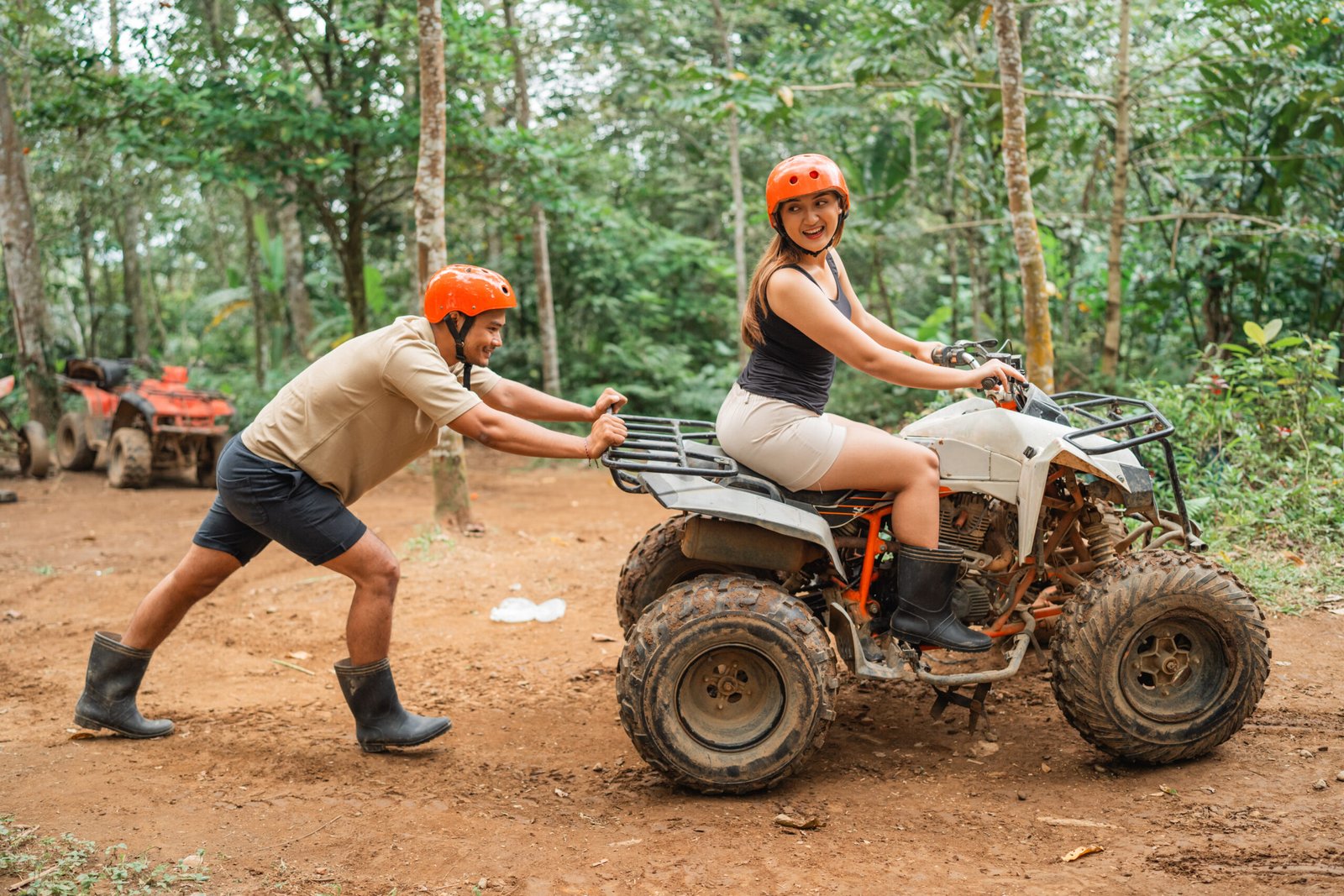 beautiful asian women looking at the asian man that pushing the atv at tracking area